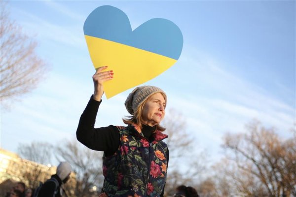 A protester holds up a cutout of a heart, in the pattern of the Ukrainian flag