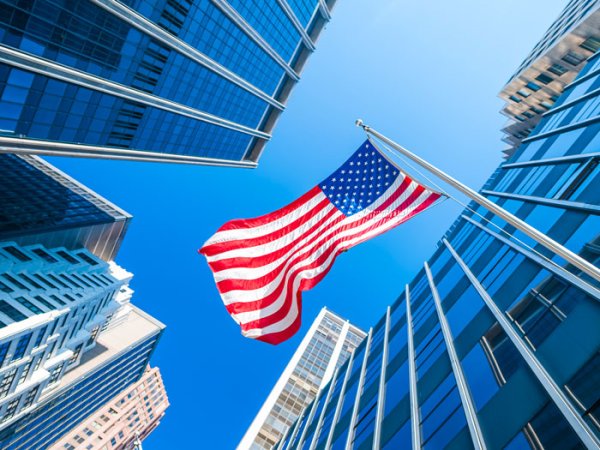 Looking up at an American flag surrounded by skyscrapers