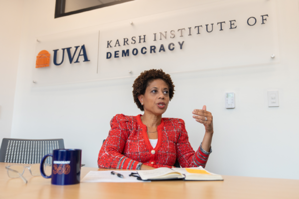 Executive Director Melody Barnes sitting at desk in front of Karsh Institute of Democracy logo sign.