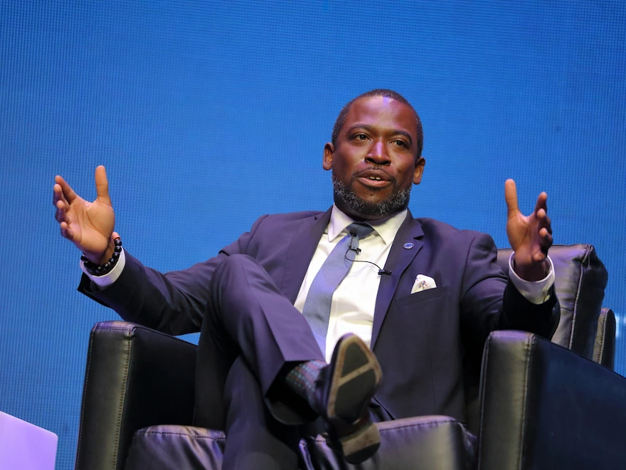 A speaker seated on stage at Democracy360