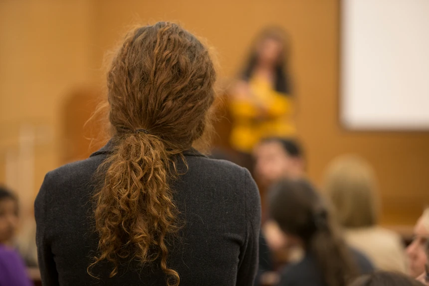 The back of a woman standing in the audience at an event