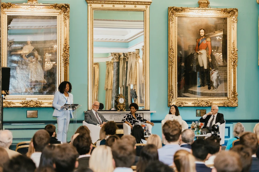 A panel of speakers seated in front of a large room of attendees at the London event